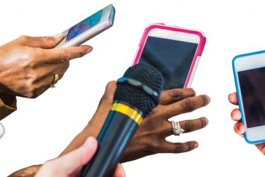 Several people holding smart phones and microphones as if recording an interview.