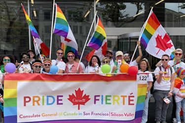 People celebrating Pride, holding a banner that reads "Pride - Fierte" and "Consulate General Consulate General of Canada in San Francisco | Silicon Valley"