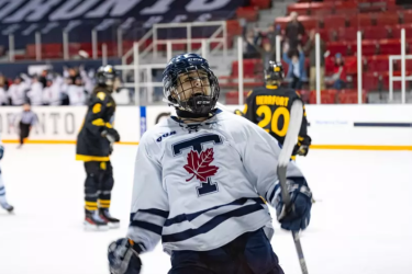 Women's hockey player celebrates after a goal while looking into the crowd.