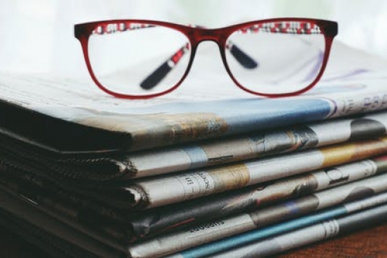 a pair of reading glasses sitting on a stack of newspapers
