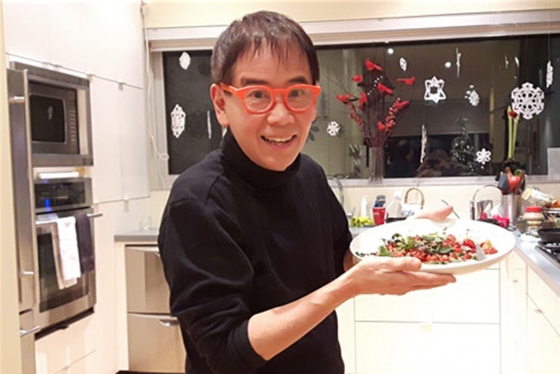 John Ota holding a dish of food in a kitchen