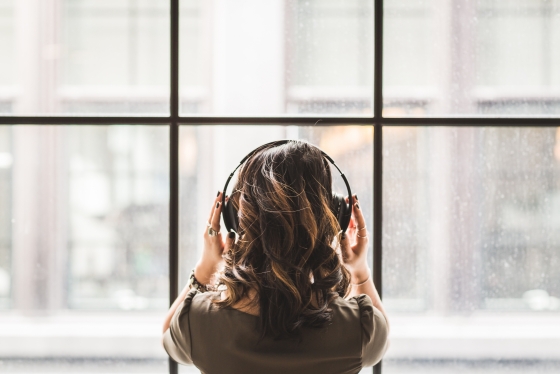 Woman listening to headphones and looking out a wall of windows