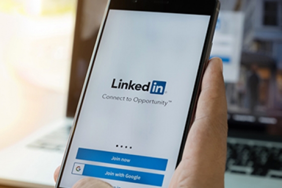 Hand holds a mobile phone with showing LinkedIn home screen