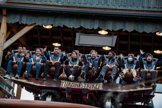 Alumni smiling at the camera while sitting at rollercoaster.