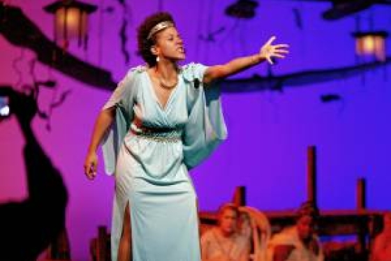 Actress in Grecian gown gesturing passionately on stage at Hart House Theatre