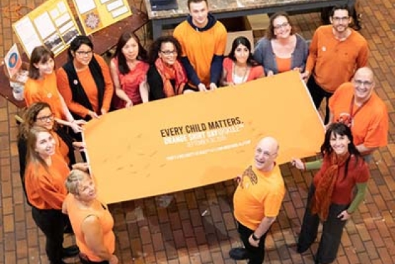 Bird's eye view of people in orange shirts holding an "Every Child Matters" sign.
