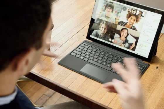 Picture of a person speaking to other people on a laptop 