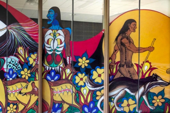A section of a mural of Indigenous artwork shows a man made of flowers next to stylized bears.