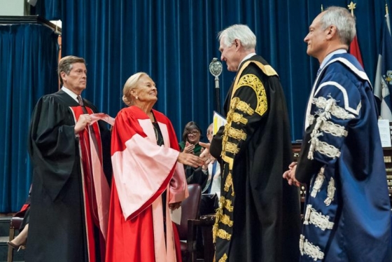 Loretta Rogers, who today received an honorary doctor of laws, honoris causa, shakes the hand of Chancellor Michael Wilson, as President Meric Gertler (right) and Toronto Mayor John Tory look on (photo by Lisa Sakulensky)
