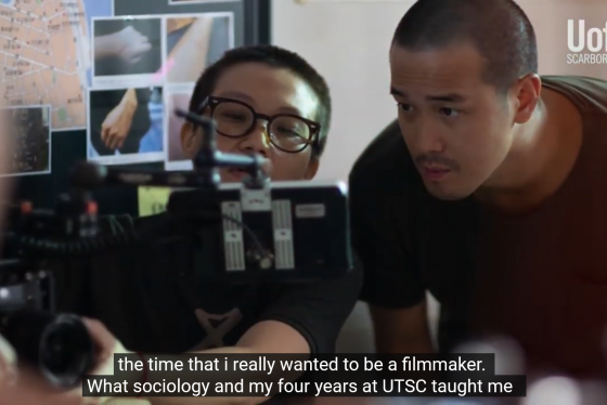 In a still from a video, Derek Tsang looks into the viewfinder of a camera.