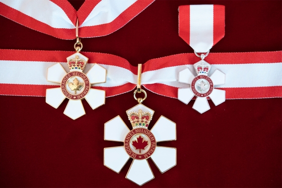 Three Order of Canada medals. The six-petalled medal has a maple leaf in the centre and hangs on a ribbon.