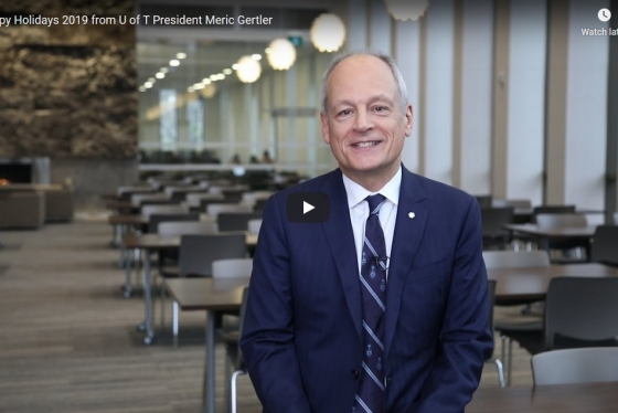 Meric Gertler smiles as he stands in a library reading room in a scene from his holiday video.