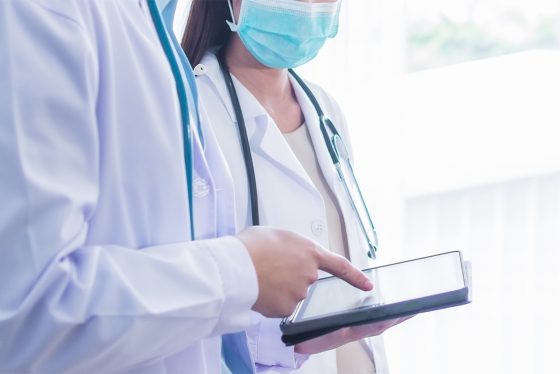 In a stock image, a man and a woman in white doctor's coats look at a tablet together.