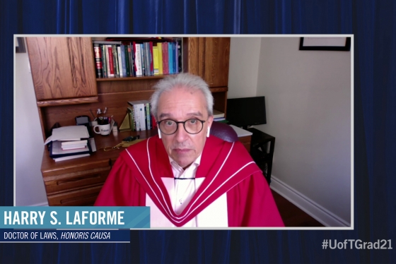 Harry LaForme, wearing his academic robes, speaks on video in front of a wooden desk and bookshelf.