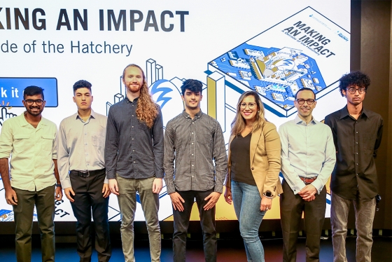 Seven people stand in front of a screen at Hatchery Demo Day. Text reads: making an impact.