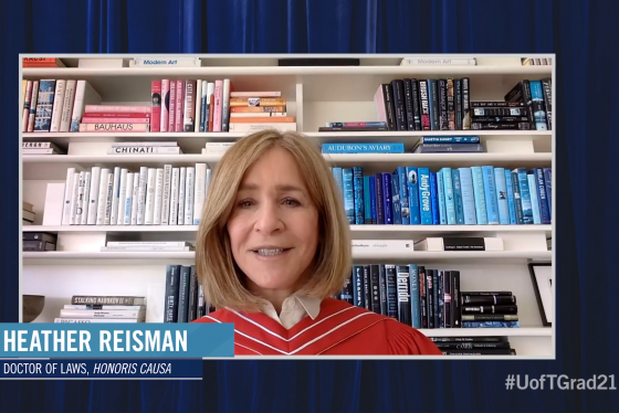 Heather Reisman, wearing academic robes, speaks on video in front of a bookcase of books arranged by colour.