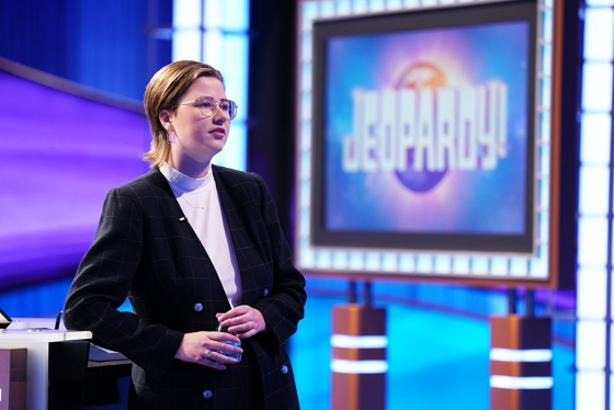 Mattea Roach stands next to a sign that says, Jeopardy!