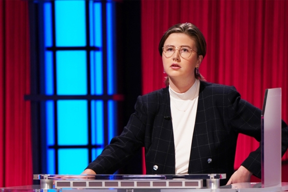 Mattea Roach looks thoughtful, standing on the Jeopardy TV set and choosing a category.