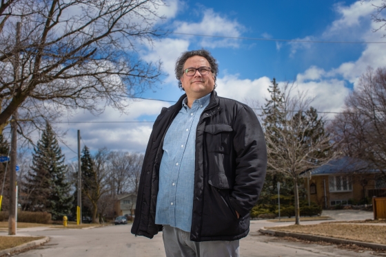 Jesse Wente smiles confidently in front of blue sky and bare tree