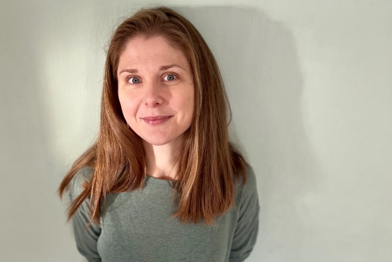 A portrait of Lucy standing in front of a wall
