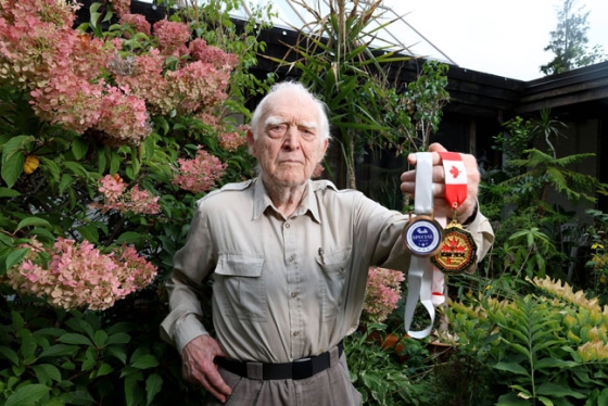 A man standing outside and holding medals