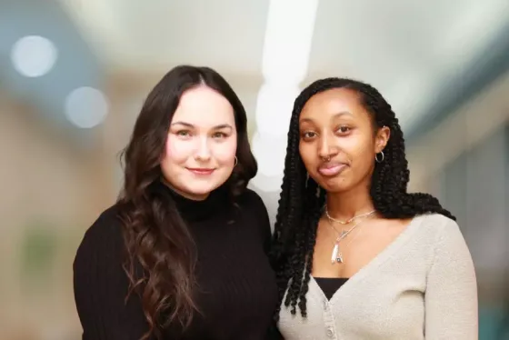 Two young women standing in front of a blurry background