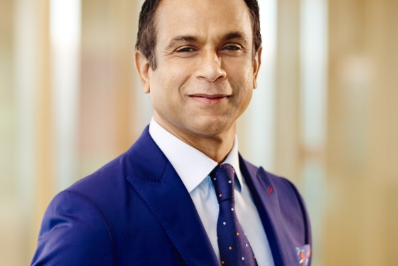 A portrait of Ramesh wearing a blue suit and tie