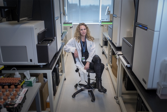 Lisa Strug sits on a chair between fridges and other lab equipment.