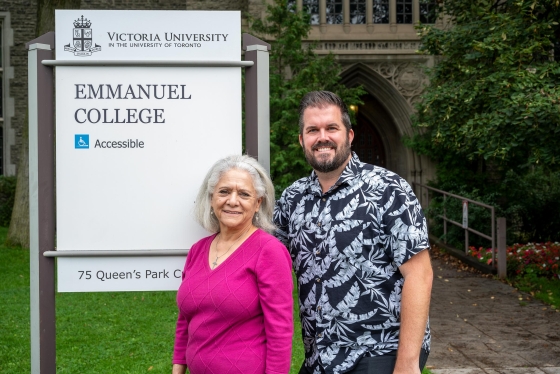 Two people standing in front of the Emmanuel College sign