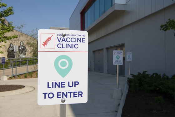 Signs outside Highland Hall read: Scarborough COVID-19 vaccine clinic, line up to enter.