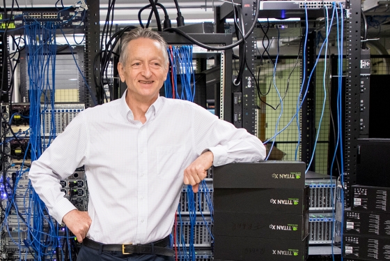Geoffrey Hinton standing in a technology lab, smiling