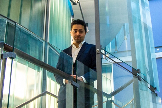 Parham Aarabi looks down from a glass-walled staircase that spirals up through an indoor courtyard.