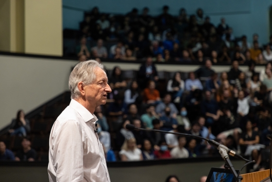 Geoffrey Hinton speaking on stage at Convocation Hall