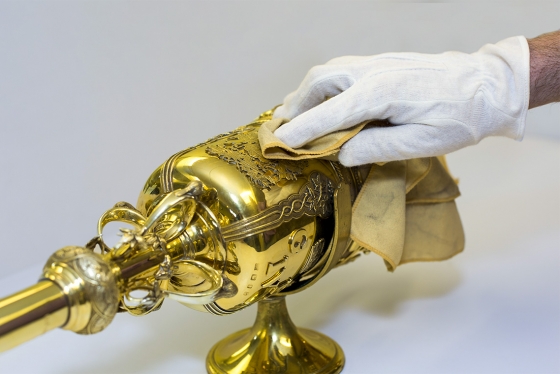A gloved hand gently dusts the elaborate gold head of U of T's ceremonial mace.