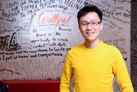 Allen Lau smiles while standing in front of a whiteboard scrawled with dozens of inspirational messages.