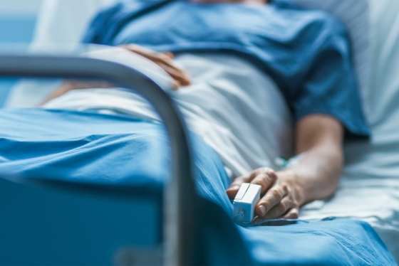 A man lies in a hospital bed with his finger in a monitoring device.