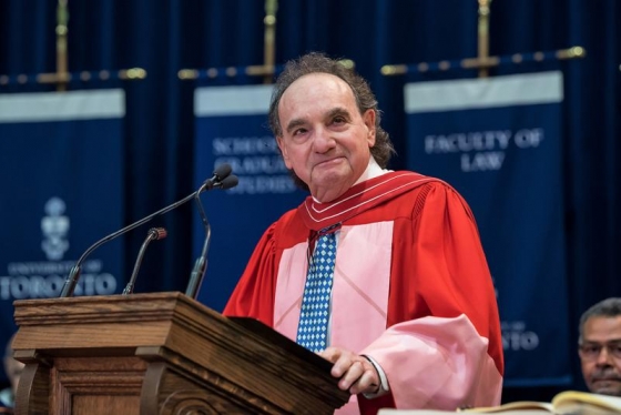 Michael Moldaver, wearing academic robes, smiles from the podium at Convocation Hall.