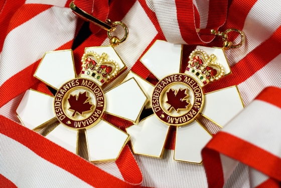 The Order of Canada medal is shaped like a six-petalled flower with a maple logo in the centre and a crown on the top petal.