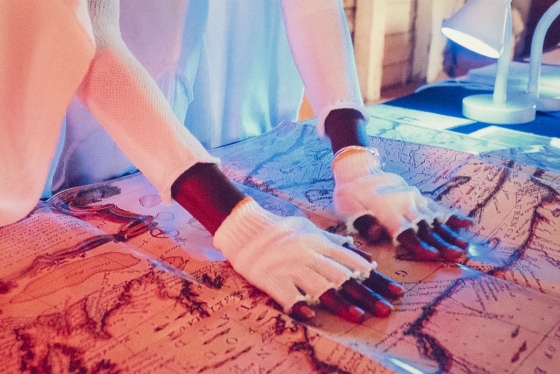 Gloved hands touching a world map laying flat on a table