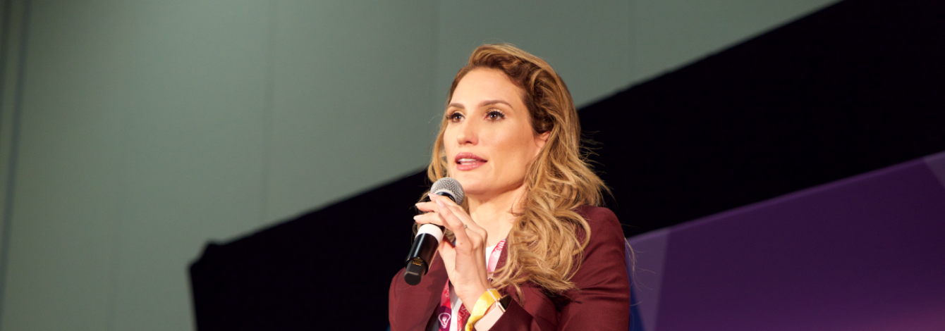Lorraine D'Alessio stands on a stage, giving a presentation.