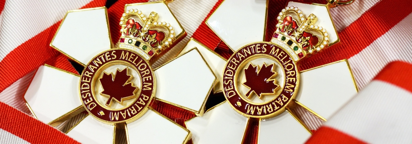 The Order of Canada medal is shaped like a six-petalled flower with a maple logo in the centre and a crown on the top petal.