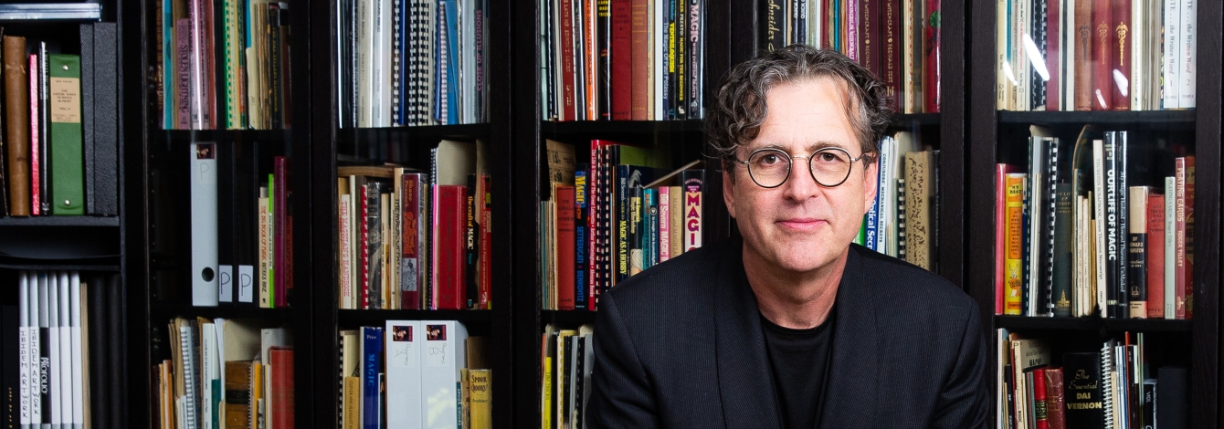Featured Alum David Ben standing in front of bookshelves