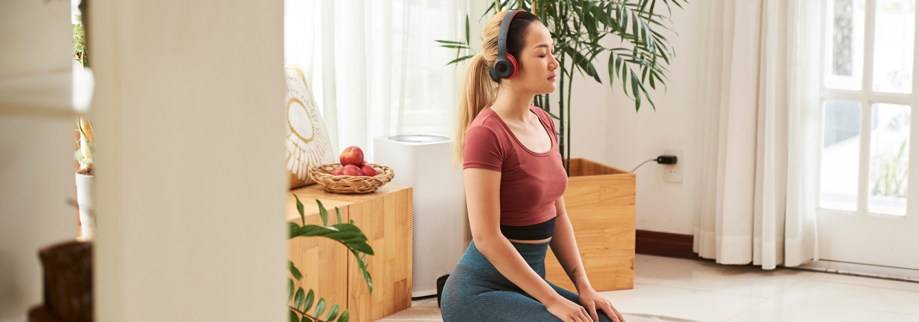 A woman kneels on her floor listening to a meditation on her phone