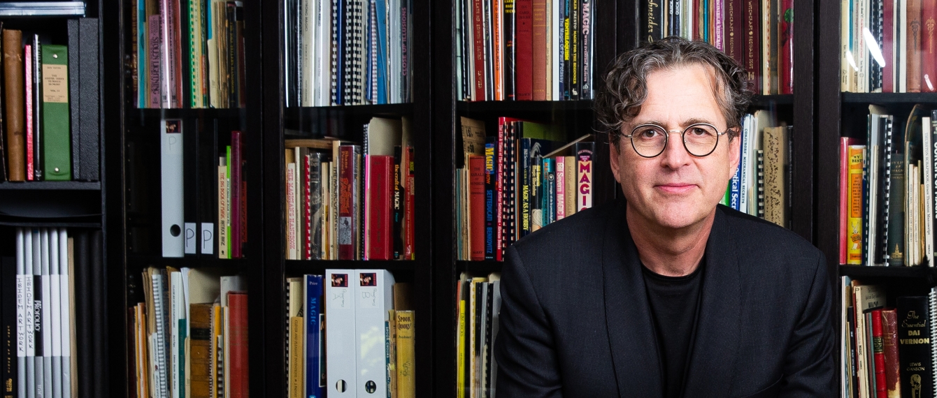 Featured Alum David Ben standing in front of bookshelves