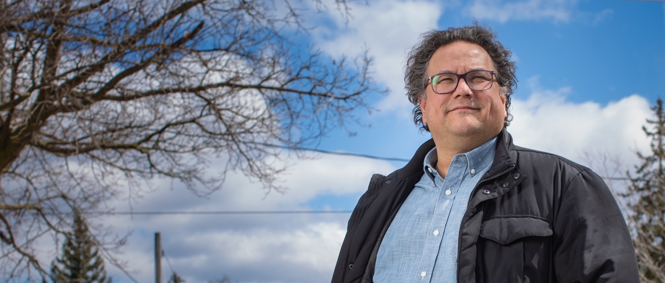 Jesse Wente smiles confidently in front of blue sky and bare tree