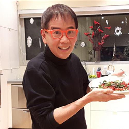John Ota holding a dish of food in a kitchen