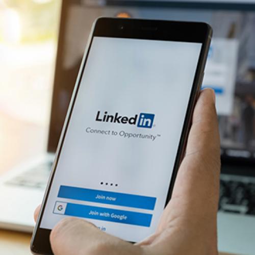Hand holds a mobile phone with showing LinkedIn home screen