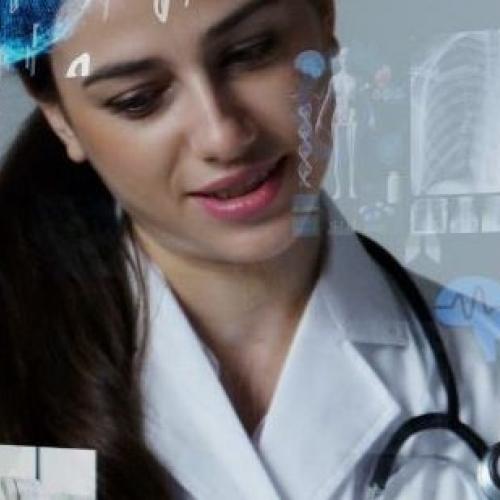 Woman in white labcoat and stethoscope with another person looking at tablet