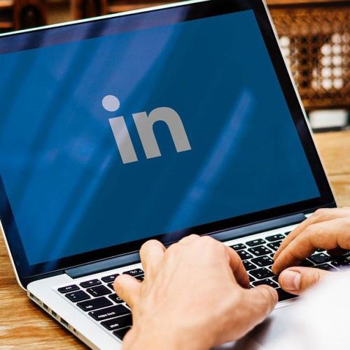 Someone typing on laptop shown LinkedIn logo on screen.