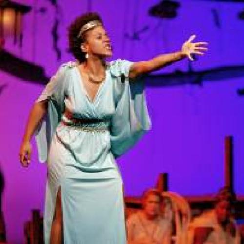 Actress in Grecian gown gesturing passionately on stage at Hart House Theatre
